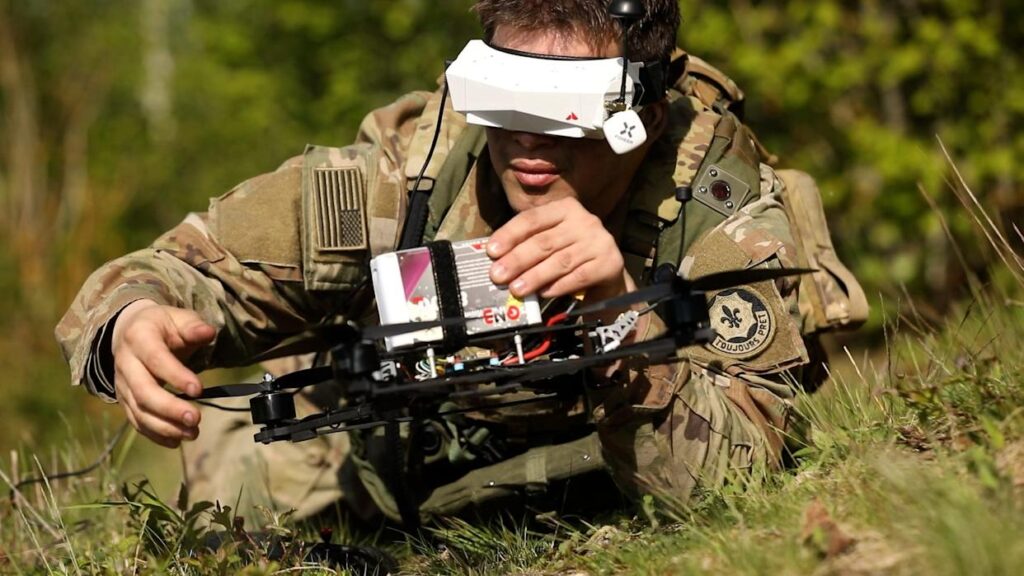 Un soldato dell'esercito statunitense con indosso delle cuffie si prepara a lanciare un drone FPV. Screenshot/Business Insider/Graham Flanagan